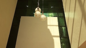 A room with a hanging light fixture, a window with green-tinted glass, and a white ceiling.