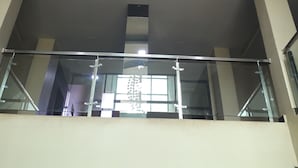 A modern interior with a hanging chandelier, glass railings, and recessed lighting.