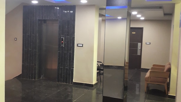 A lobby with a black elevator, a reception desk, and a seating area.
