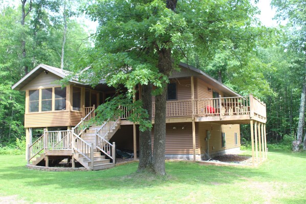 A wooden cabin with a balcony, a staircase, and a large tree in front. - Northwoods Wisconsin Retreat!!  Newly built cabin sleeps 12 comfortably.   (Trego)