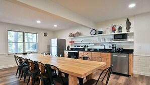 Una cocina moderna con una mesa de comedor de madera, sillas negras y un refrigerador de acero inoxidable.