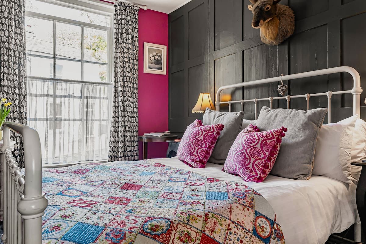 Un lit avec une couette aux couleurs vives, une tête de lit et des coussins décoratifs.