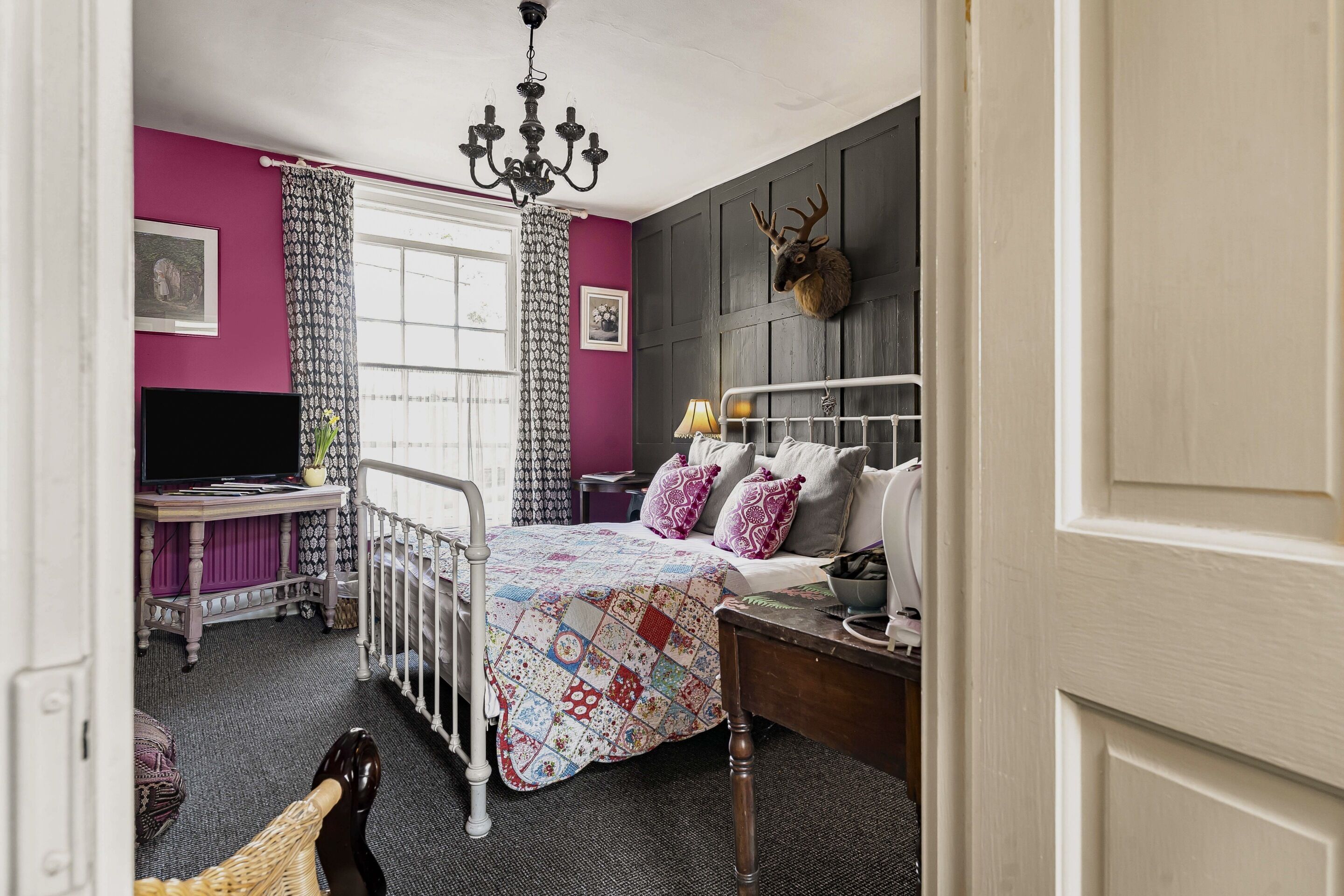Un dormitorio con cama, escritorio, televisor y candelabro.