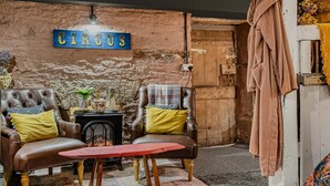 A cozy room with a leather armchair, a small table, a fireplace, and a sign that reads 'CIRCUS'. - One Drake Road Hotel (Tavistock)