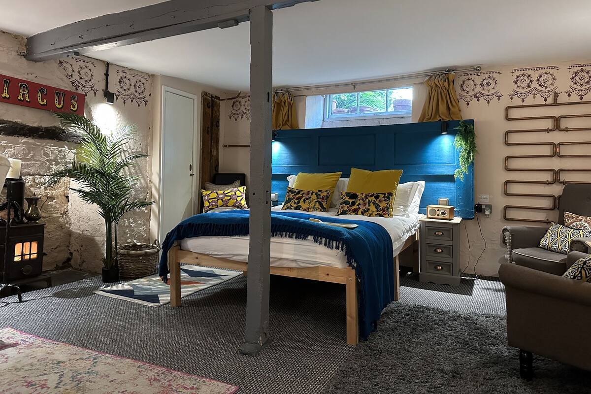 Une chambre à coucher avec un lit, une table de chevet, une chaise, une lampe et une fenêtre.