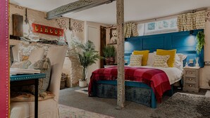 A bedroom with a bed, a desk, a chair, a potted plant, and a wall sign. - One Drake Road Hotel (Tavistock)