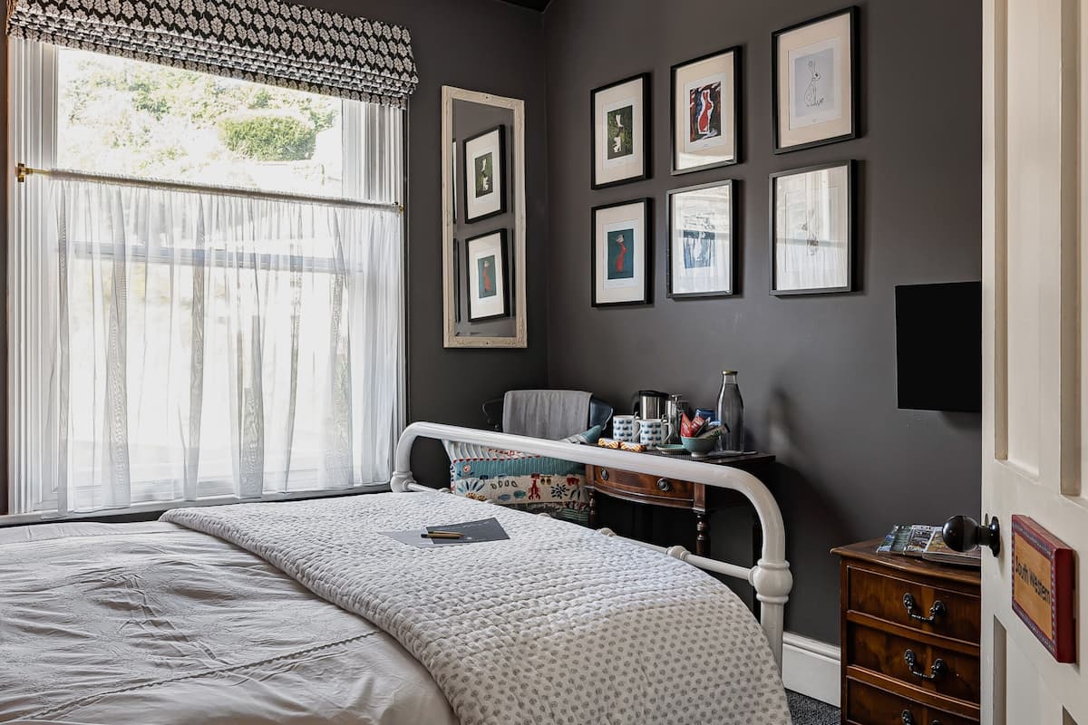 Une chambre à coucher avec un lit, une commode, une chaise et un mur orné de tableaux.