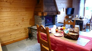 Una cabaña acogedora con chimenea de piedra, paredes de madera y un comedor con mantel rojo.