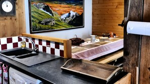 Una cocina con encimera de madera, un lavamanos, una estufa y un cuadro de montañas en la pared.