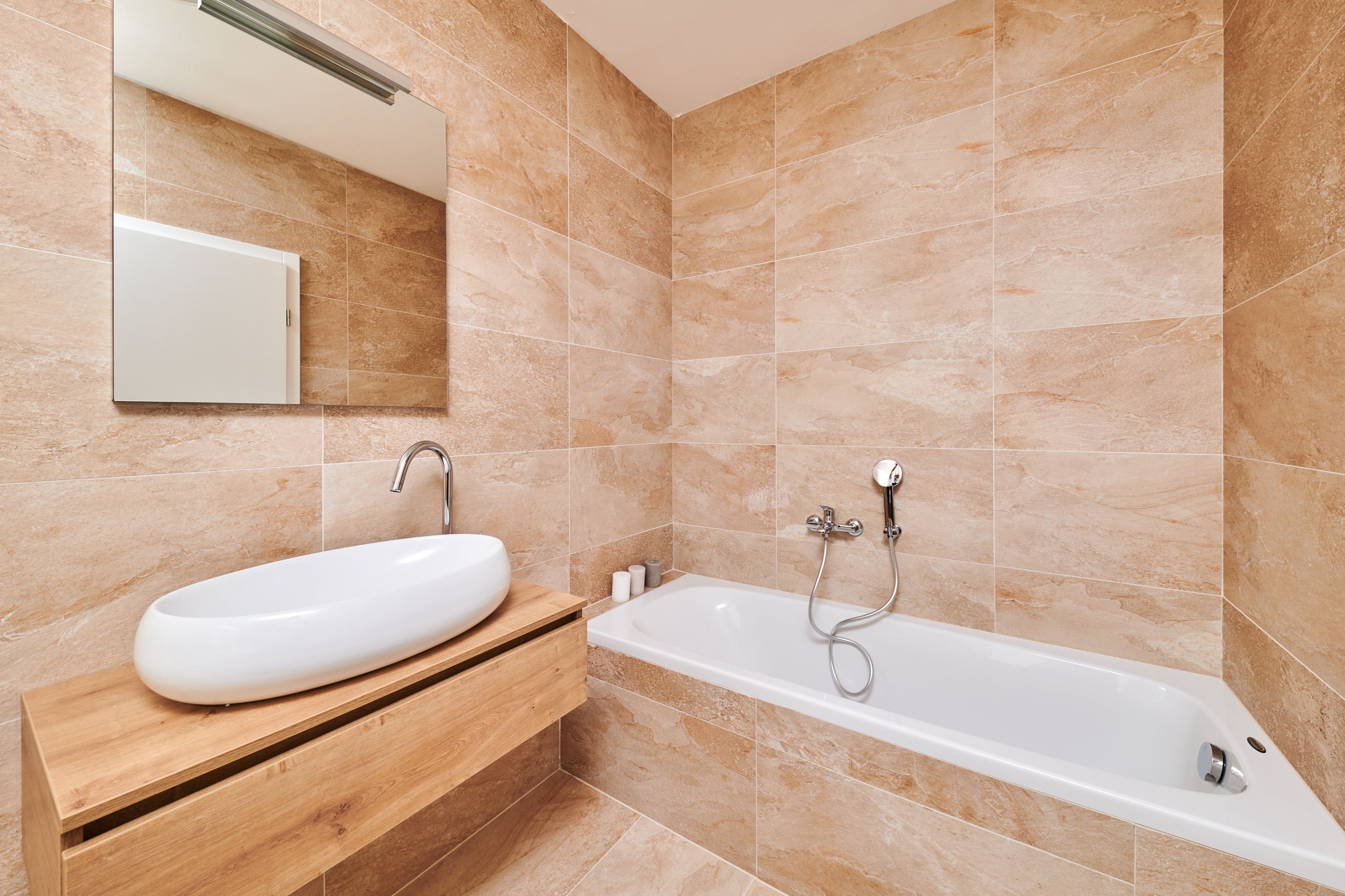 Ein modernes Badezimmer mit Waschbecken, Holz-Waschtisch und freistehender Badewanne.