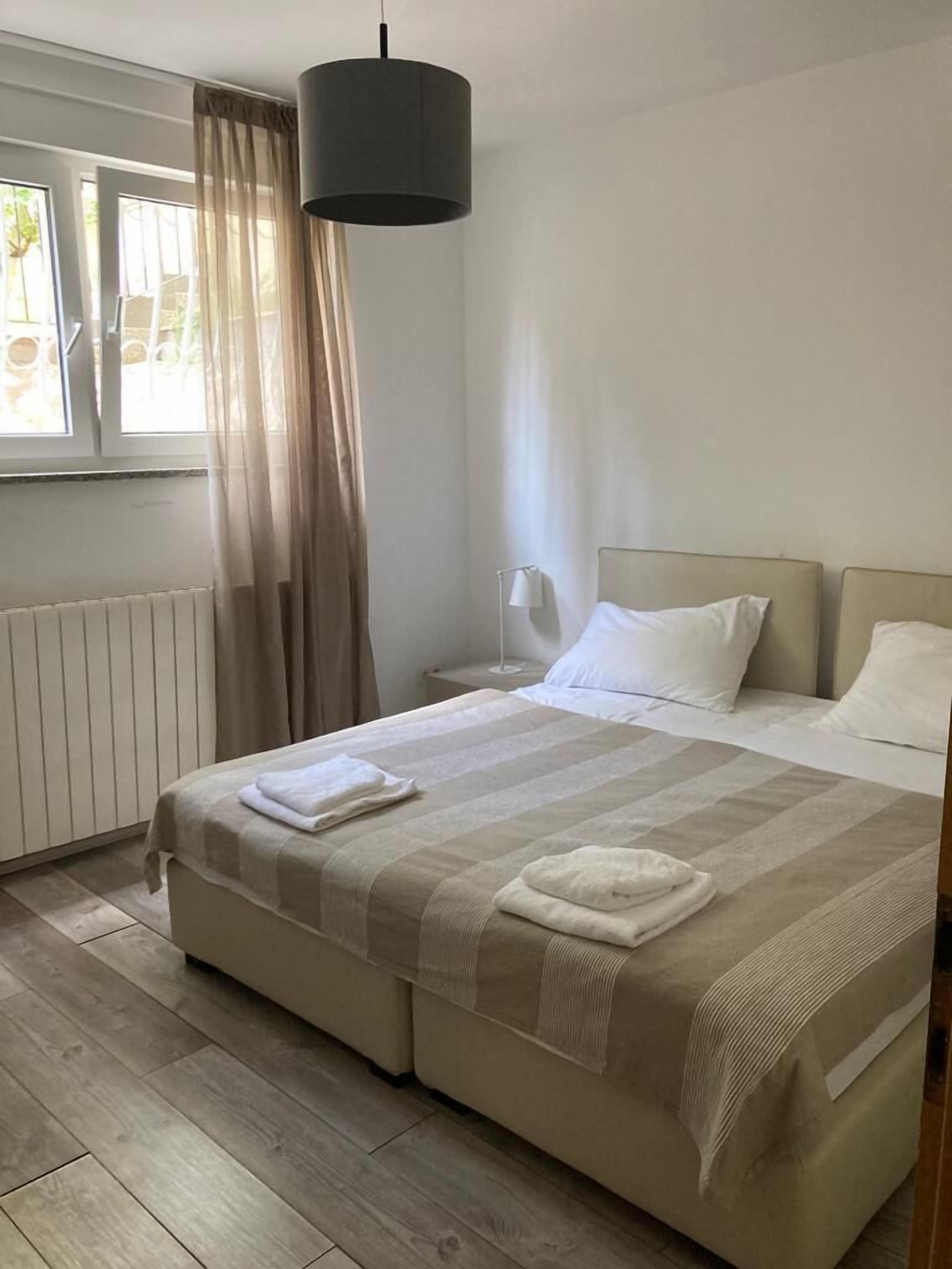 Een hotelkamer met een groot bed, een nachtkastje, een lamp en een raam met gordijnen.