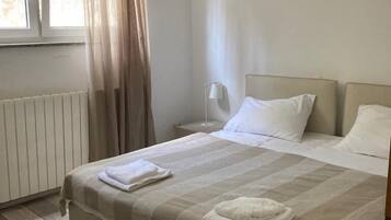 Een hotelkamer met een groot bed, een nachtkastje, een lamp en een raam met gordijnen.