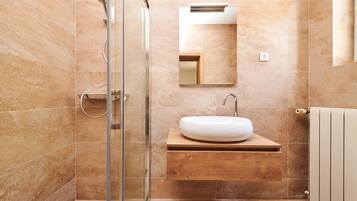 A modern bathroom with a glass shower enclosure, a wooden vanity with a white sink, and a mirror above the sink.