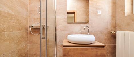 A modern bathroom with a glass shower enclosure, a wooden vanity with a white sink, and a mirror above the sink.