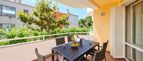 A balcony with a table, chairs, and a fruit bowl.