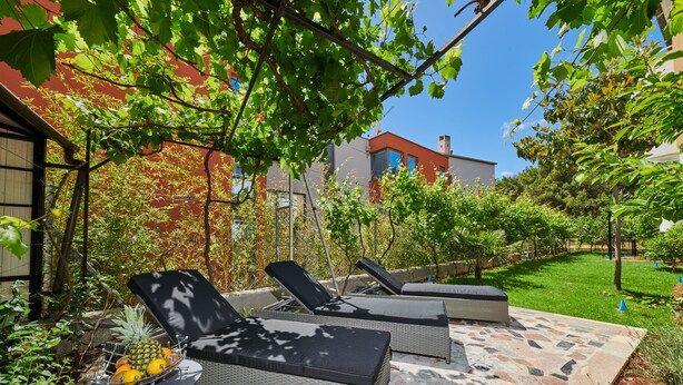 A patio area with two lounge chairs, a small table with fruits, and a tiled floor. - Villa Marija (Pula)