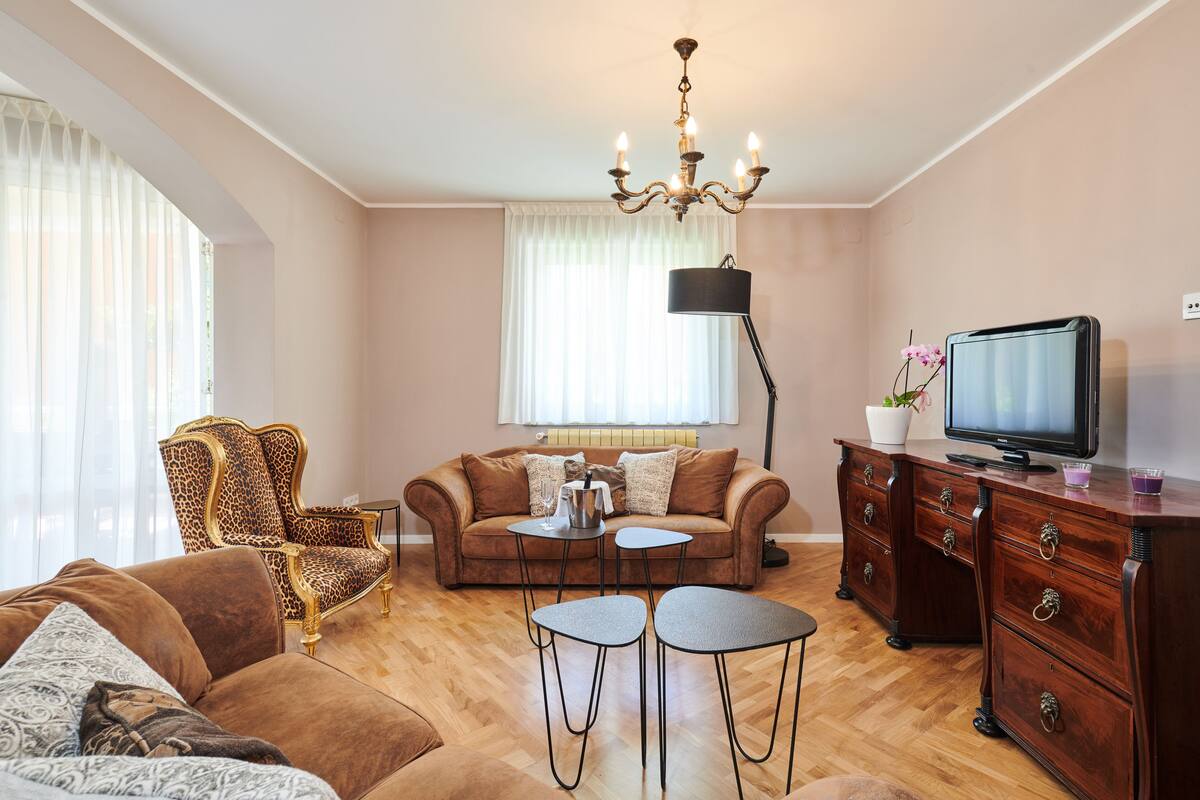 A living room with a sofa, armchair, coffee table, TV, and a fireplace.