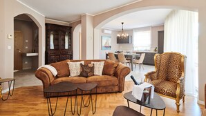 A spacious living room with a brown sofa, a leopard print armchair, and a dining area in the background. - Villa Marija (Pula)