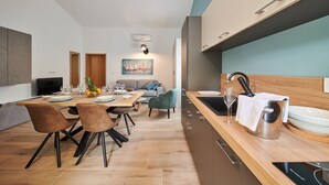 A modern kitchen with a wooden countertop, stainless steel sink, and a dining area with a table set for four. - Villa Marija (Pula)