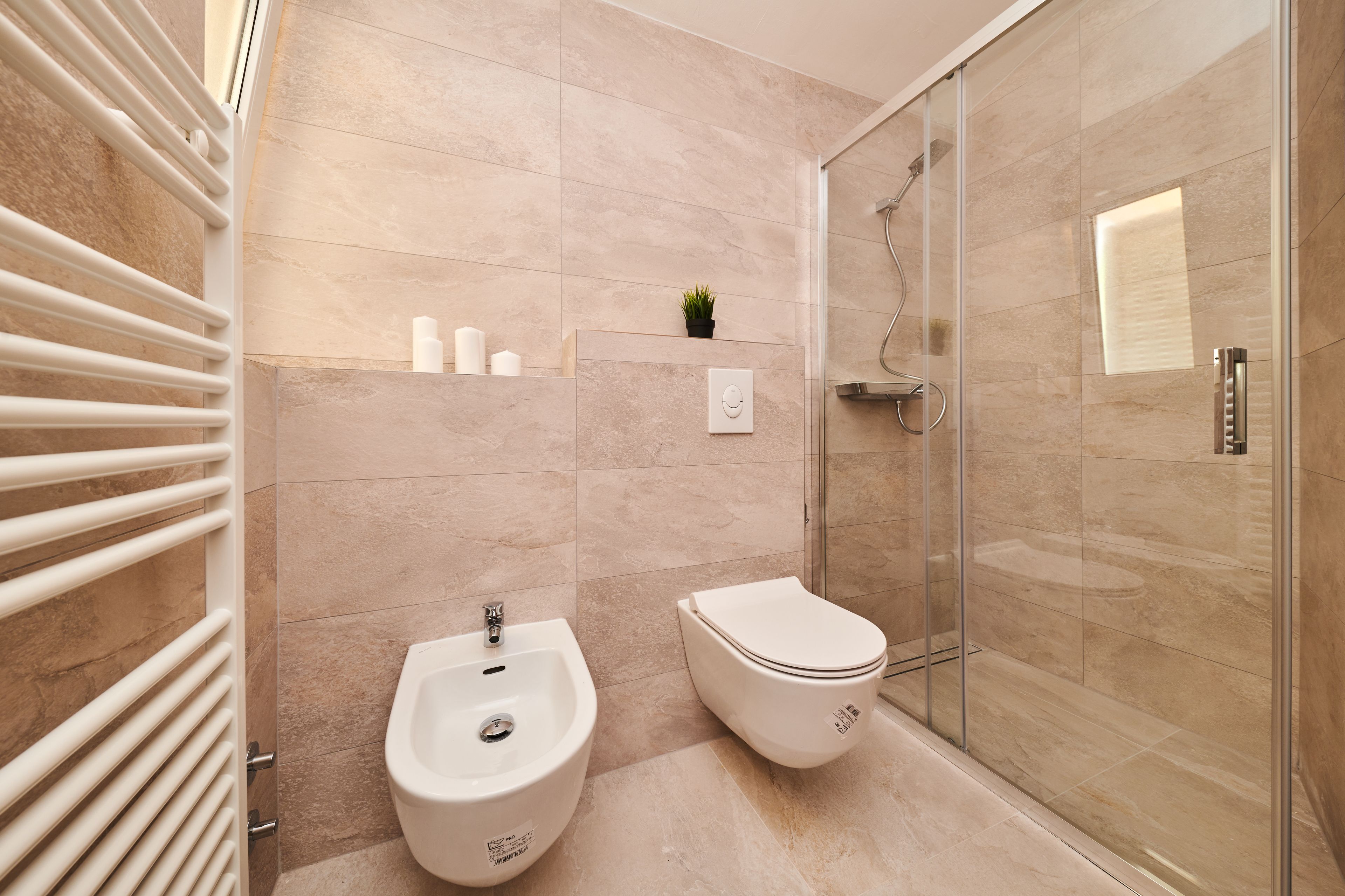 Un baño moderno con bidé, inodoro y cabina de ducha de vidrio.