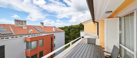 Uma varanda com mesa e cadeiras, vista para edifícios vizinhos e céu claro.