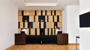 A reception area with a wooden panel wall, two receptionists, and a black desk.