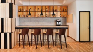 A modern bar area with wooden shelves, black pendant lights, and three bar stools.