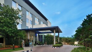 A modern building with a covered entrance, paved walkway, and landscaped garden areas.