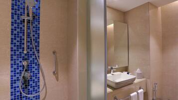 A modern bathroom with a glass shower enclosure, a sink with a mirror, and a towel rack.