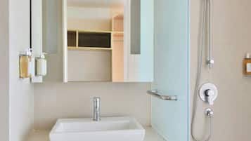 Un baño moderno con un lavamanos blanco, un espejo, una ducha y un perchero para toallas.