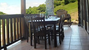 Une terrasse couverte avec un mur en pierre, des meubles en bois et des lanternes suspendues.