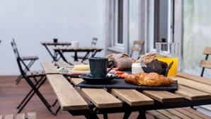 Un esmorzar amb un croissant, un muffin, un got de suc d'aranja i una tassa sobre una taula de fusta.