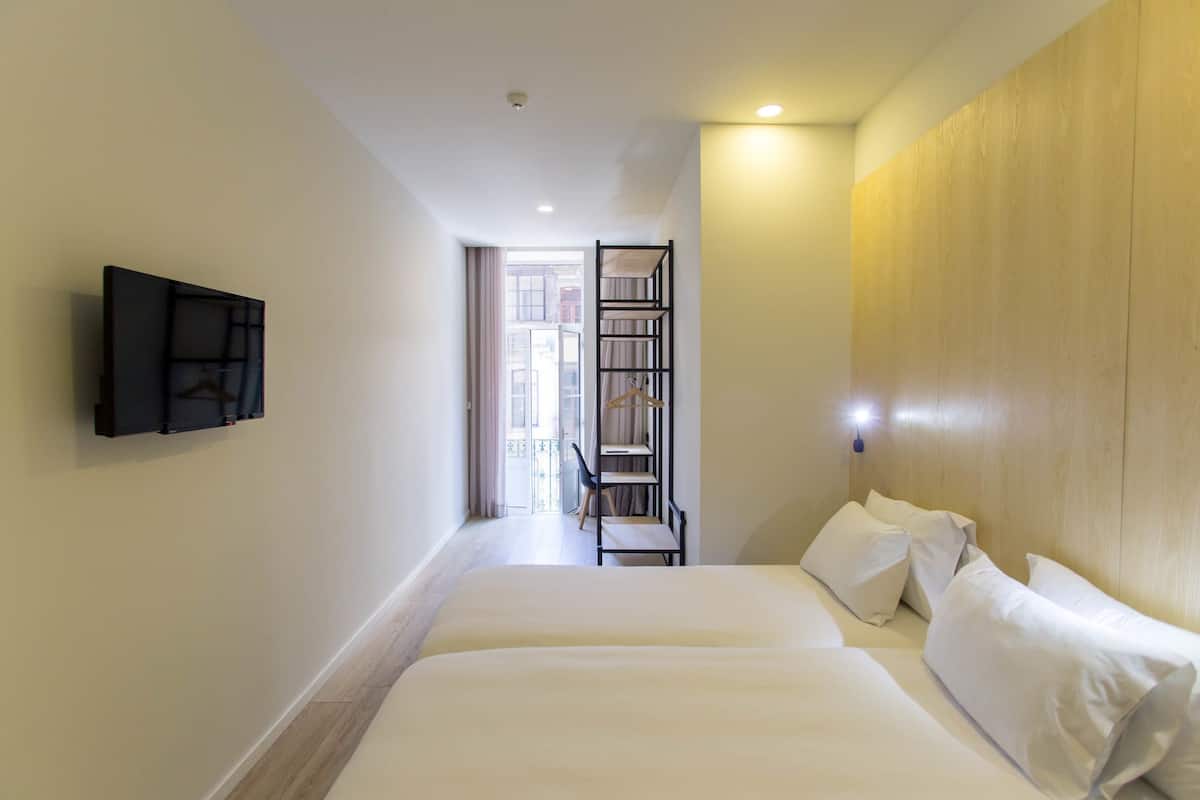 A hotel room with two beds, a TV mounted on the wall, and a wooden panel on the wall.