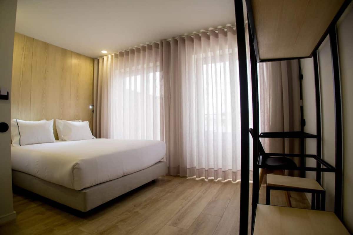 A bedroom with a bed, a desk, and a chair.