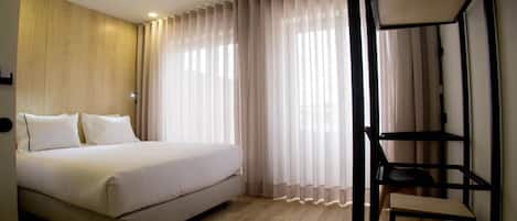 Quarto com cama, escrivaninha e cadeira.