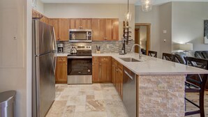 Une cuisine moderne avec des meubles en bois, des appareils en acier inoxydable, un grand îlot central et un luminaire suspendu.