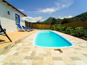 Una piscina al aire libre, sombrillas, sillones reclinables de piscina