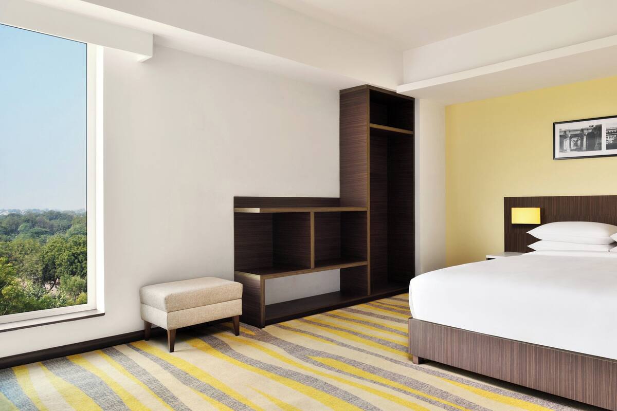 Ein Hotelzimmer mit großem Fenster, einem Bett, einem Einbauschrank und einer kleinen Sitzecke.