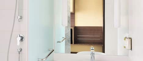A modern bathroom with a white sink, a large mirror, and a shower enclosure.