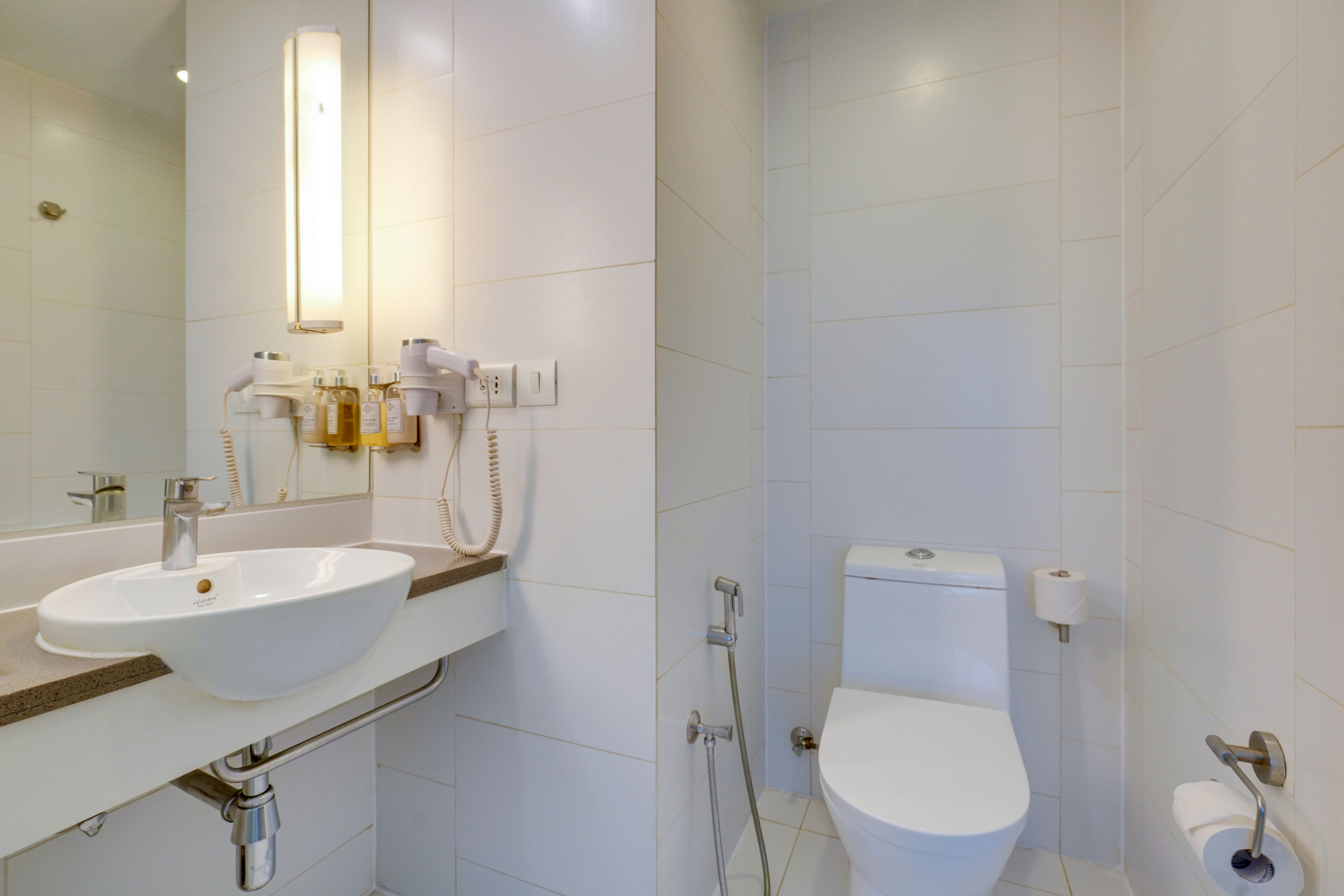 Een moderne badkamer met een wit wastafel, toilet en douche.