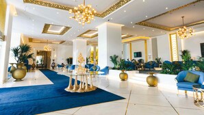 Un hall d’entrée spacieux, doté d’un tapis bleu, de touches dorées et de mobilier moderne.