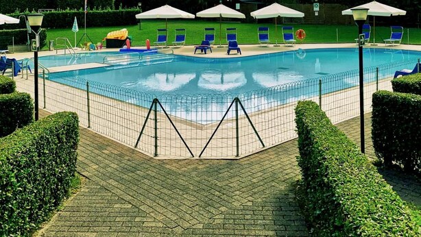 A swimming pool with lounge chairs and umbrellas, surrounded by neatly trimmed hedges and a mountainous backdrop. - Aurelia Rta Detta Il Cascinale (Montignoso)