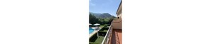 A balcony with a view of a swimming pool, a mountain, and a clear sky. - Aurelia Rta Detta Il Cascinale (Montignoso)