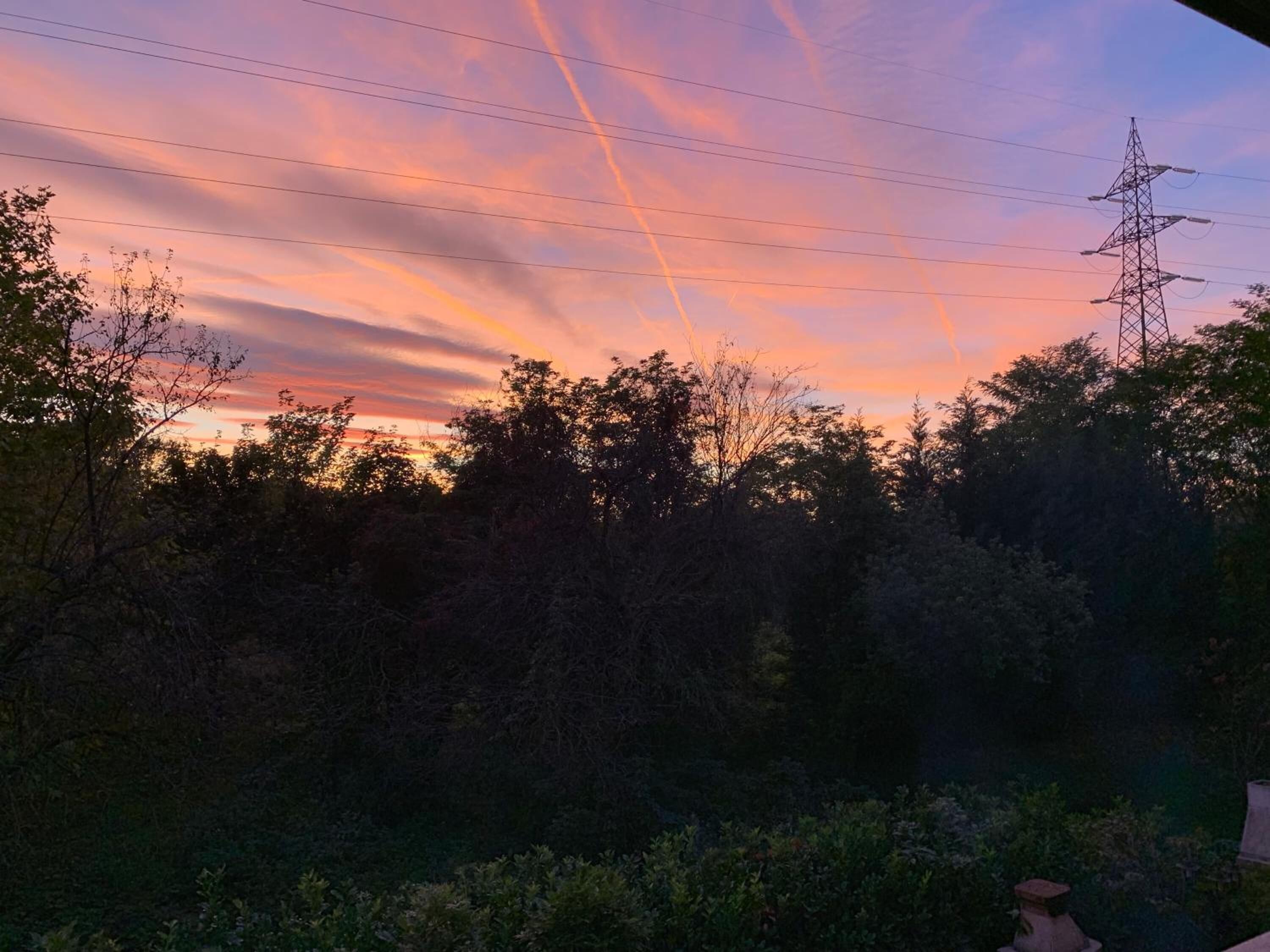 A sunset with power lines and a transmission tower in the background.