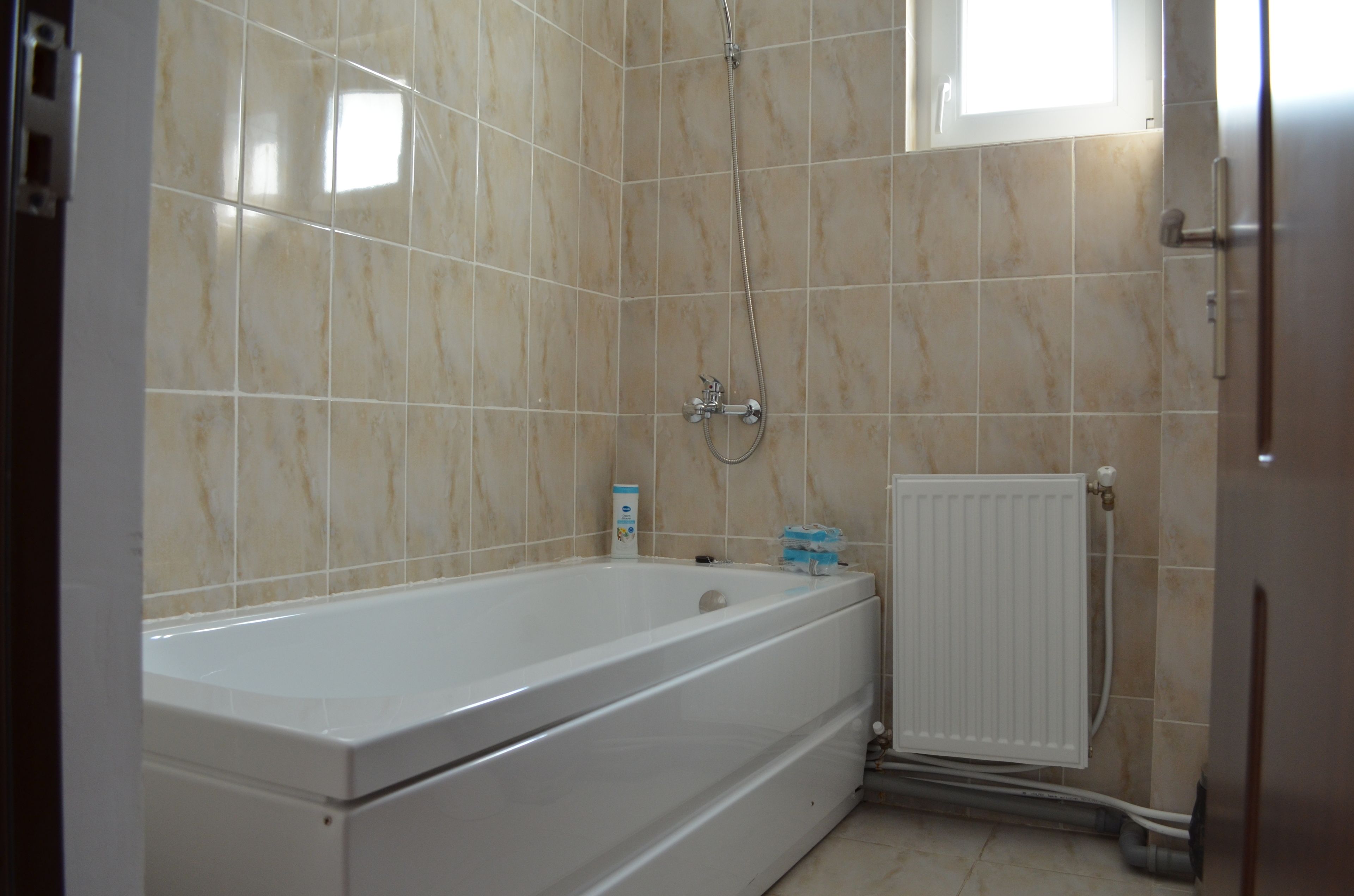 Un baño con bañera, ducha y un radiador blanco.