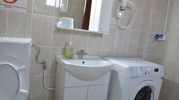 A bathroom with a toilet, sink, and washing machine.