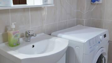 A bathroom with a sink, a washing machine, and a mirror.