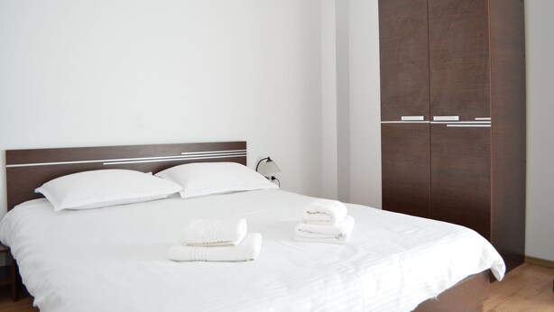 A neatly made bed with white linens and two folded towels on the bed. - Alexys Residence 6 (Iasi)