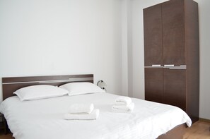A neatly made bed with white linens and two folded towels on the bed. - Alexys Residence 6 (Iasi)