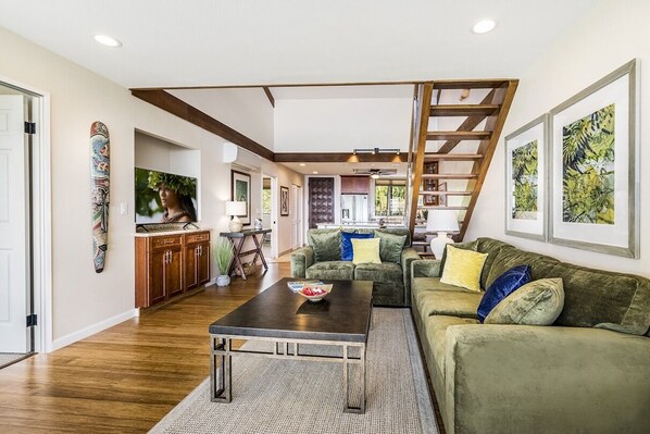 A spacious living area with a wooden staircase, a green sofa, and a coffee table.